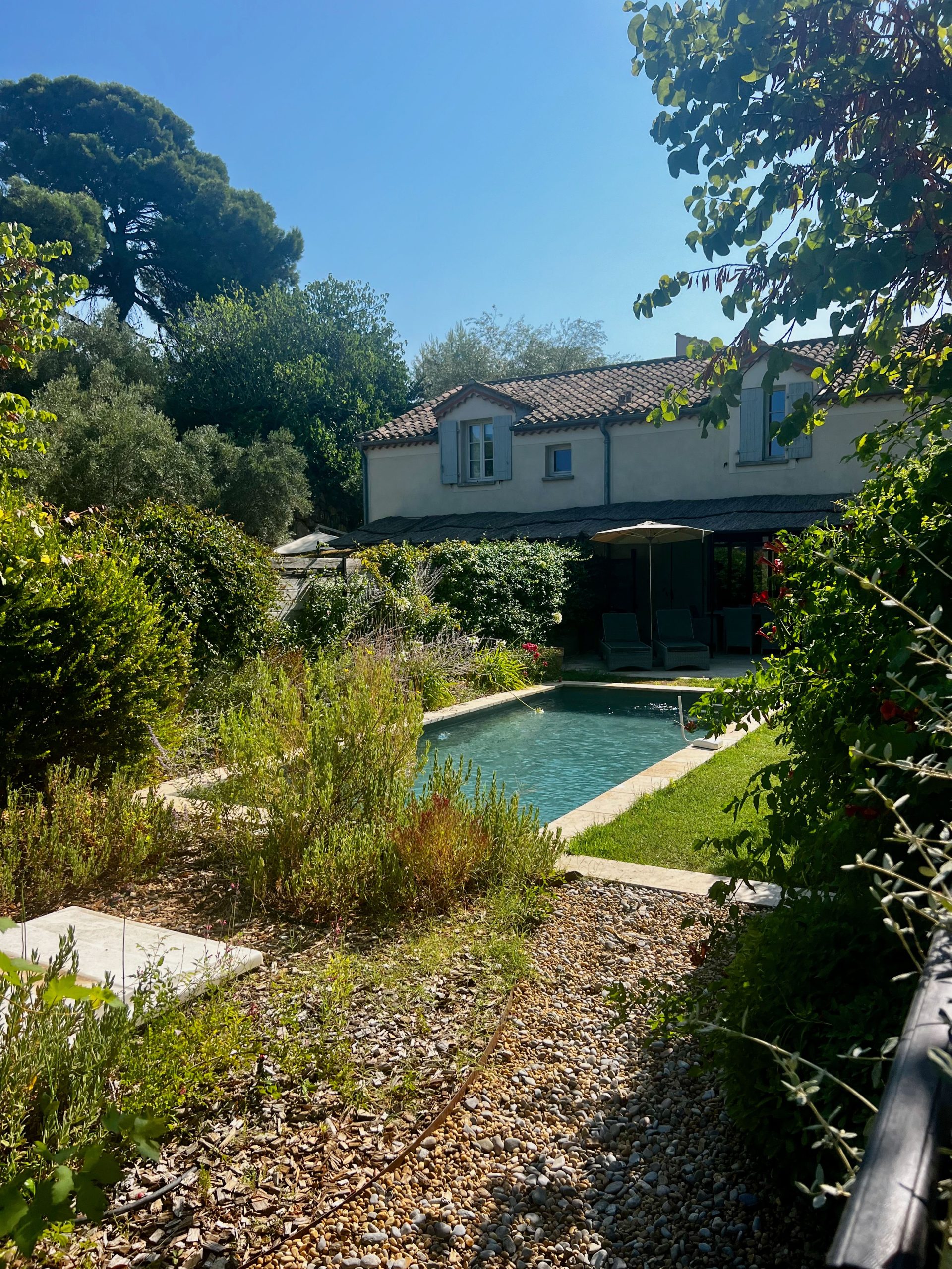 Picturesque view of a cottage with a serene garden and pool, ideal for a summer retreat.